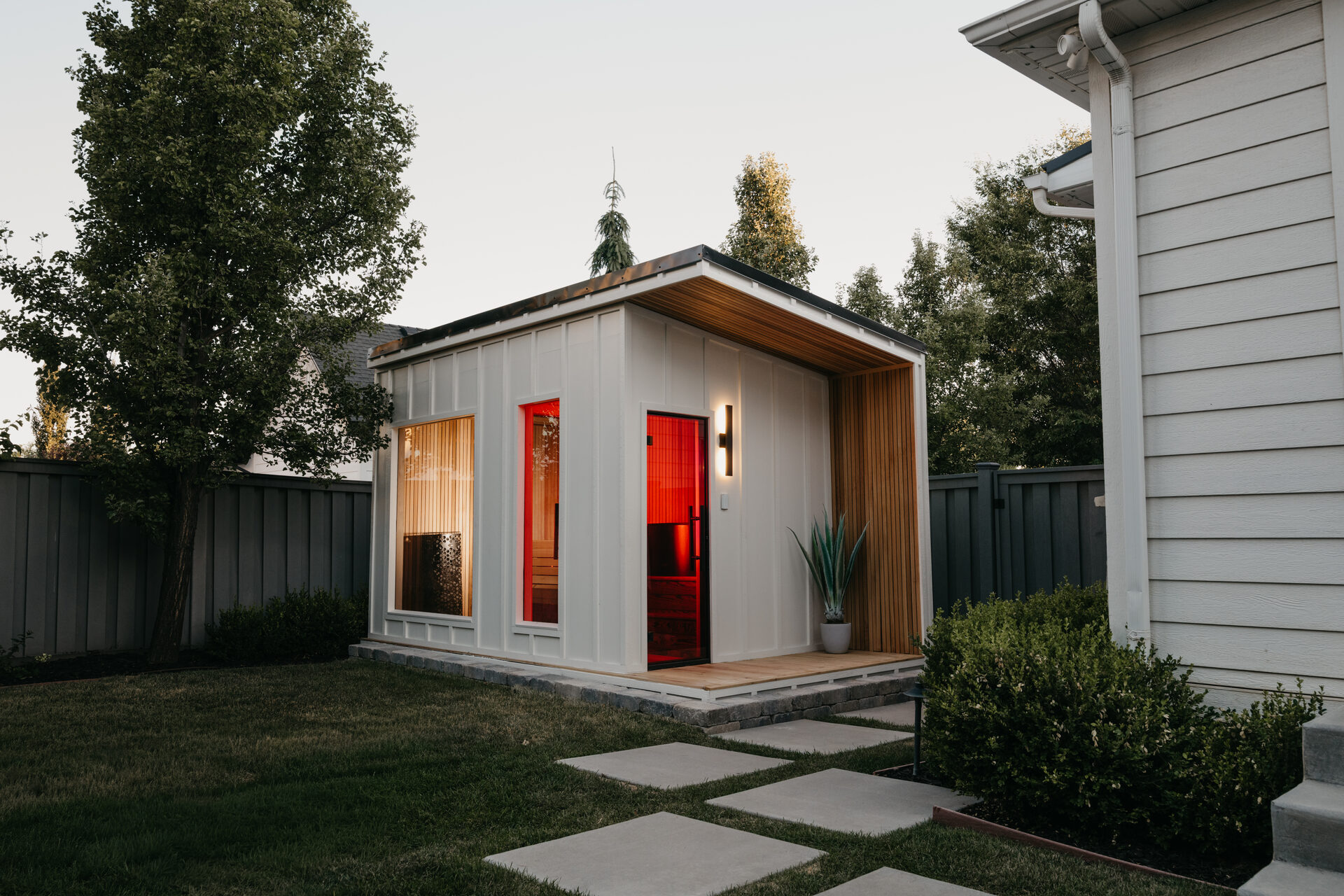 A finished New Primitive sauna in a backyard at dusk